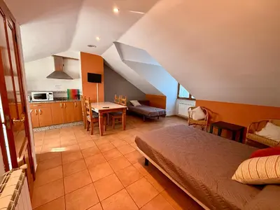 a bedroom with a bed and a table and a kitchen at Hostal El Horno in Molinaseca