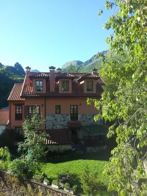 a large yellow house with a balcony at Apartamentos Rurales Buenamadre in Pola de Somiedo
