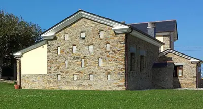 a large brick building with grass in front of it at Apartamentos Rurales Casanova in Tapia de Casariego
