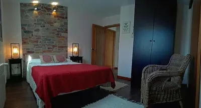 a bedroom with a bed and a stone wall at Apartamentos Rurales Casanova in Tapia de Casariego