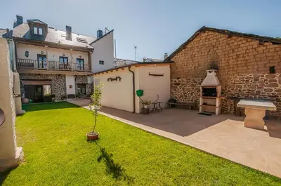 a yard with a stone building with a table and a bench at Casa Rural El Almendro De Maria in Ponferrada