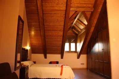 a bedroom with wooden ceilings and a bed in a room at Casa Rural El Almendro De Maria in Ponferrada
