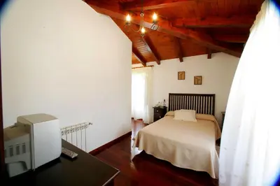 a bedroom with a bed and a desk with a tv at Casa da Botica A Estrada in Os Casares