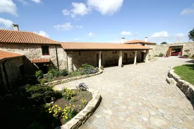 a stone building with a courtyard with flowers at Casa da Botica A Estrada in Os Casares