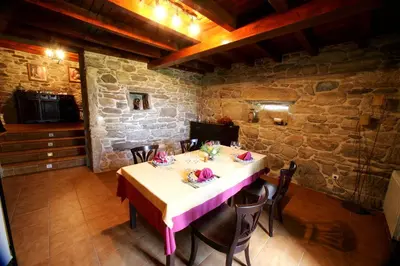 a table in a room with a stone wall at Casa da Botica A Estrada in Os Casares