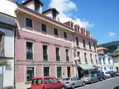 a pink building with cars parked in front of it at Hotel Nueva Allandesa in Pola de Allande