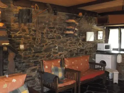 a living room with two chairs and a stone wall at Carriles Romanos in Odollo