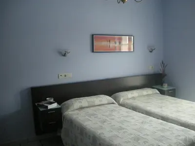 a bedroom with two beds and a picture on the wall at Apartamentos Casa Germana in Tapia de Casariego