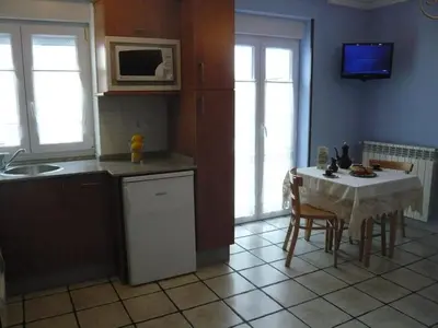 a kitchen with a table and a kitchen with a sink and a microwave at Apartamentos Casa Germana in Tapia de Casariego