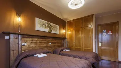 a bedroom with two beds and a wooden wall at H Rural Chamouco in Bóveda