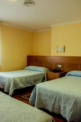 two beds in a room with yellow walls at Hotel Mabú in Ourense