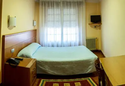 a small bedroom with a bed and a window at Hotel Mabú in Ourense