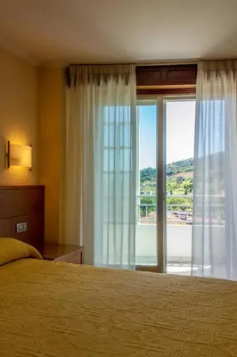 a bedroom with a bed and a large window at Hotel Mabú in Ourense