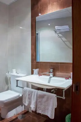 a bathroom with a sink and a toilet and a mirror at Hotel Mabú in Ourense