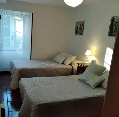 a room with two beds and a lamp and a window at Casa Laguiñas en Castro Caldelas in Castro Caldelas