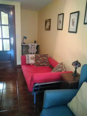 a living room with a red couch and a table at Casa Laguiñas en Castro Caldelas in Castro Caldelas
