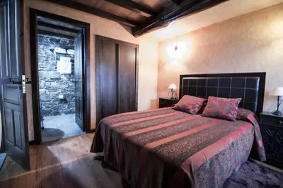 a bedroom with a bed and a door to a bathroom at Apartamentos A Casa Nova in A Pontenova