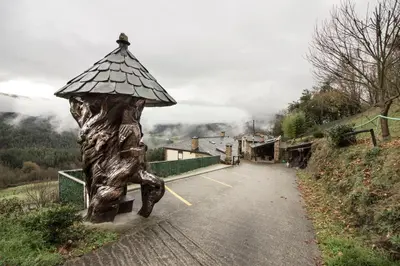 a statue of a person holding an umbrella on a road at Apartamentos A Casa Nova in A Pontenova
