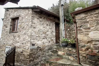 an old stone building with potted plants on it at Apartamentos A Casa Nova in A Pontenova