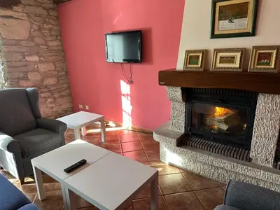 a living room with a fireplace and a tv at Oktheway Casa da Escola in Sarria