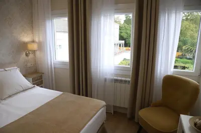 a bedroom with a bed and a chair and a window at Aires do Umia in Caldas de Reis