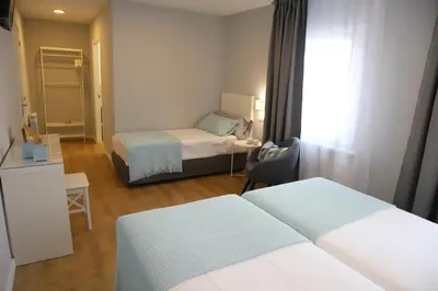 a hotel room with two beds and a window at Aires do Umia in Caldas de Reis