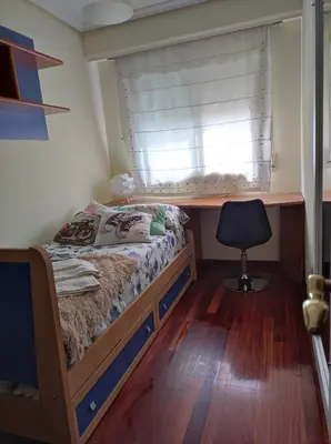 a bedroom with a bed and a window with a chair at Piso zona Campus-Lagunas in Ourense
