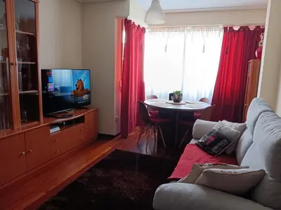 a living room with a couch and a tv and a table at Piso zona Campus-Lagunas in Ourense