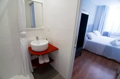 a white bathroom with a sink and a bed at Alojamientos MYL in Arzúa
