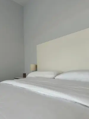 a white bed with white sheets and a night stand at Lemos Sol in Monforte de Lemos
