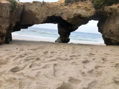an arch in the sand on a beach with the ocean at El Rinconcito de Foz in Foz