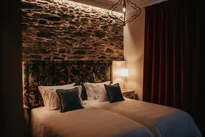 a bedroom with a large bed with a stone wall at 1930 Boutique Hotel in Arzúa