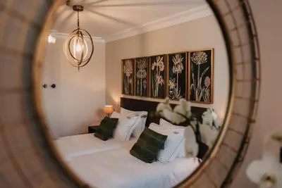 a mirror reflecting a bed with white sheets and pillows at 1930 Boutique Hotel in Arzúa