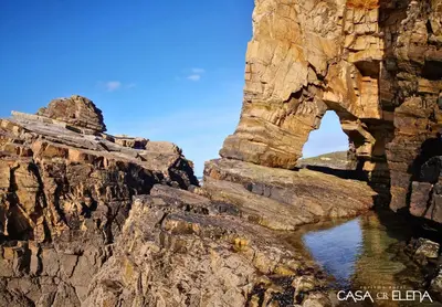 an arch in the rocks next to a body of water at Casa Elena Turismo Rural in Reinante