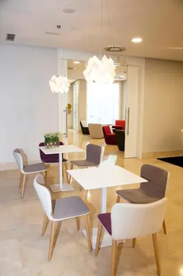 a waiting area with tables and chairs in a room at Hotel Gelmírez in Santiago de Compostela