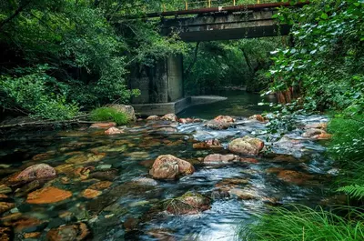 a river with rocks and a bridge over it at Casa Do Concello in Arnado
