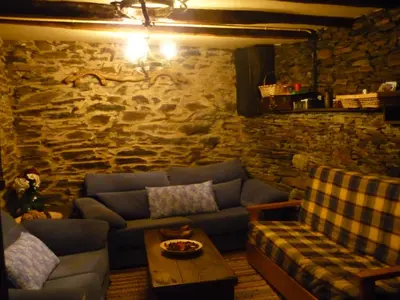 a living room with a blue couch and a stone wall at Casa Do Concello in Arnado