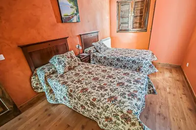 two beds in a room with orange walls at Hotel Rural Pajarapinta in Molinaseca