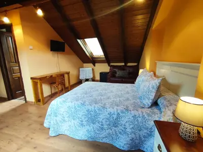 a bedroom with a large bed with a blue blanket at Hotel Rural Pajarapinta in Molinaseca