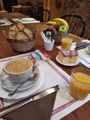 a table with a cup of coffee and a plate of bread at Hotel Rural Pajarapinta in Molinaseca