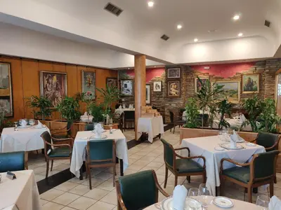 a restaurant with white tables and chairs and plants at Hotel Chef Rivera in Padrón
