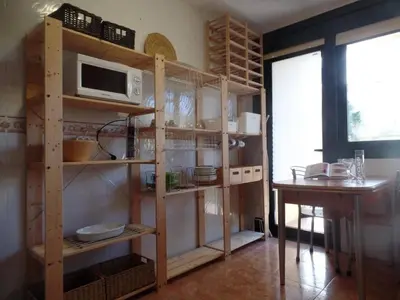a kitchen with wooden shelves with a microwave and a table at PISO ACOGEDOR EN SADA COZY FLAT IN SADA WiFi in Sada