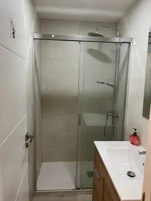 a shower with a glass door next to a sink at Albergue Azabache in Santiago de Compostela