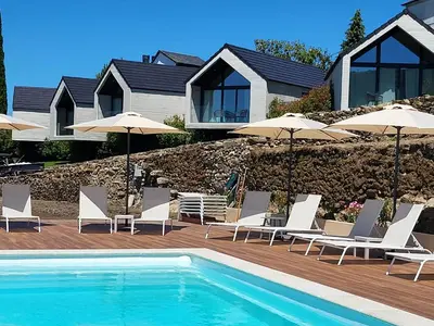 a pool with chairs and umbrellas next to a house at Miradores do Sil Hotel Apartamento in Cristosende
