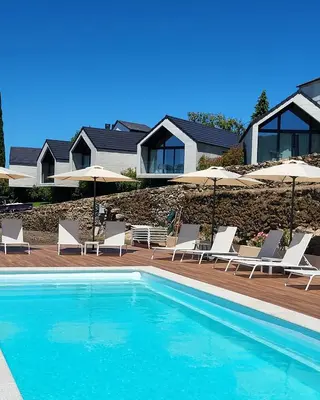 a swimming pool with chairs and umbrellas at Miradores do Sil Hotel Apartamento in Cristosende