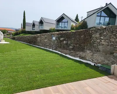 a stone retaining wall in front of a house at Miradores do Sil Hotel Apartamento in Cristosende