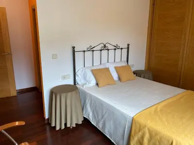 a bed with two pillows and a stool in a room at Carmen in Caldas de Reis