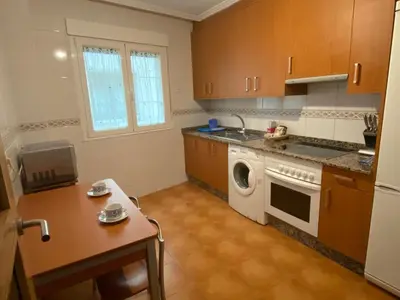 a kitchen with a washing machine and a table at Carmen in Caldas de Reis