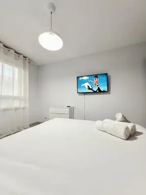 a bedroom with a white bed with a tv on the wall at Lemos Luna in Monforte de Lemos