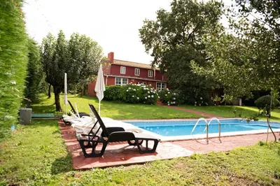 a swimming pool in a yard with two lawn chairs at Casa de Piñeiro y SPA Opcional con coste extra in Santiago de Compostela